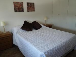 Un dormitorio con una cama blanca con almohadas. en Torre Malvinas, en Punta del Este