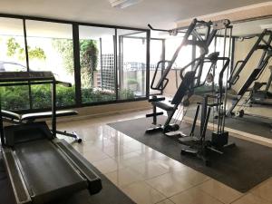 un gimnasio con cintas de correr y elípticas en una habitación con ventanas en Estudio en el Golf, en Santiago