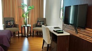 a room with a tv and a table with chairs at Mama Studio Inn in Kota Bharu