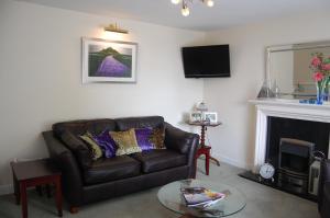 a living room with a leather couch and a fireplace at Warwick House in Penzance