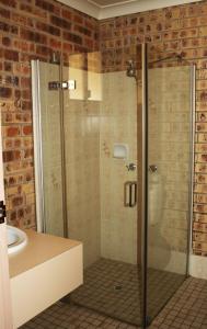 a bathroom with a glass shower with a sink at Clermont Country Motor Inn in Clermont
