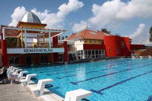 a large swimming pool in front of a building at Thermál Panzió in Mórahalom