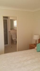 a bedroom with a bed and a bathroom with a toilet at Alexander Drive B & B in Esperance