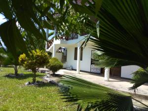 a white house with trees in front of it at Sea Breeze Villas Kenya in Diani Beach