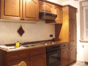 cocina con armarios de madera, fregadero y fogones en Ferienwohnungen Seidenweber, en Schmallenberg