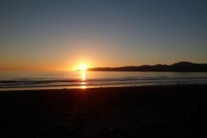 a sunset on the beach with the sun setting at Dream Escape for 2 in Paraparaumu Beach