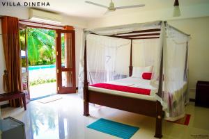 a bedroom with a canopy bed and a sliding glass door at Villa Dineha in Hikkaduwa