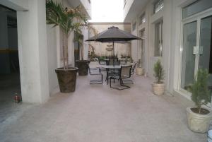 un patio con mesa, sillas y sombrilla en Savoy Express en Torreón