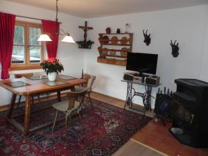 a living room with a table and a tv at Haus am See in Ramsau