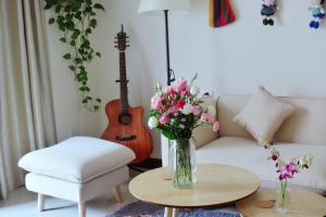 a living room with a vase of flowers and a guitar at Lan House Youth Apartment in Guangzhou