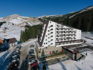 a large building with cars parked in a parking lot at Hotel Pestera in Sinaia