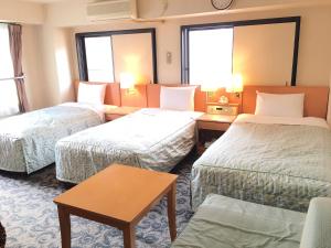 a hotel room with two beds and a table at Business Inn Sennichimae Hotel in Osaka