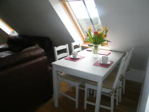 a white dining room table with a vase of flowers on it at Higher Greenway Annexe in Brixham