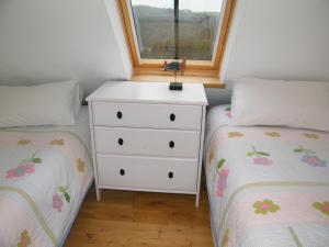 a bedroom with two beds and a dresser with a window at Higher Greenway Annexe in Brixham