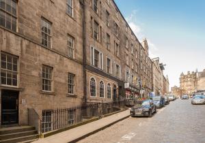 una calle con coches estacionados junto a un gran edificio de ladrillo en Blair St Scott apt Old Town, en Edimburgo
