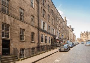 uma rua com carros estacionados ao lado de um grande edifício de tijolos em Blair St Burns apt Old Town em Edinburgo