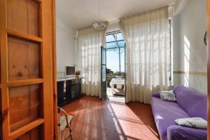 a living room with a purple couch and a sliding glass door at B&B Iris in Conca dei Marini