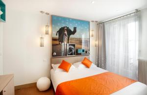 ein Schlafzimmer mit einem Bett mit orangefarbenen Kissen in der Unterkunft Hôtel Mayet in Paris