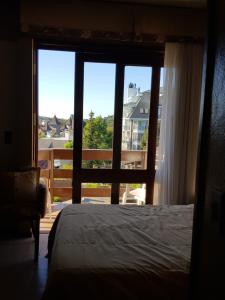 a bedroom with a bed and a large window at Residencial Pousada do Serrano in Gramado