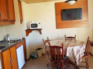 a small kitchen with a table and a microwave at Residencial Pousada do Serrano in Gramado