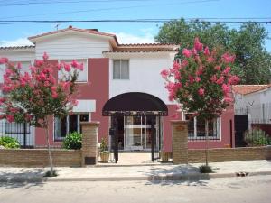 a pink and white house with two trees at Hotel Altas Cumbres in Villa Carlos Paz