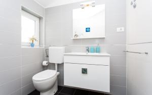 a white bathroom with a toilet and a sink at Apartments Matea in Baška +55 photos