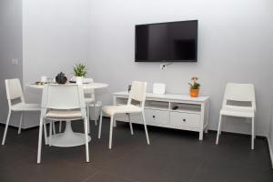 una sala da pranzo con sedie bianche, tavolo e TV di Residenza Spinelli a Napoli