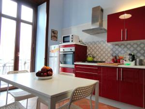 een keuken met rode kasten en een tafel met een fruitschaal bij Umberto I Holiday House in Napels