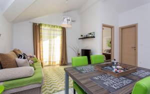 a living room with a table and green chairs at Apartments Matea in Baška