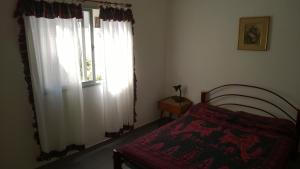 1 dormitorio con 1 cama y una ventana con cortinas blancas en Departamento Carlos Paz en Villa Carlos Paz