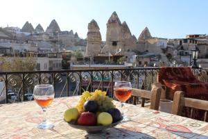 eine Schale Obst auf einem Tisch mit zwei Gläsern Wein in der Unterkunft Hanzade Cappadocia in Goreme