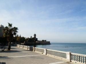 a walkway next to the ocean with a white fence at Luminoso Apartamento En El Centro De Cadiz in Cádiz