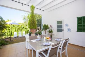 a white dining room with a table and chairs at Tres Pins in Colonia de Sant Pere