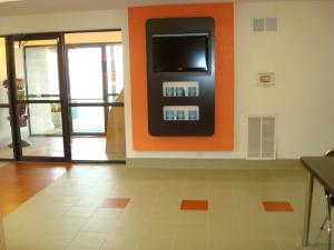 a room with an orange wall with a tv on the wall at Motel 6-Arkadelphia, AR in Arkadelphia