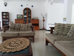 a living room with two couches and a table at Hotel Ocean View Cottage in Hikkaduwa