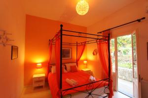 een slaapkamer met een hemelbed met oranje muren bij Angeliki Studio & Apartment in Gaios