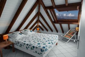 1 dormitorio con 1 cama y 1 silla en el ático en Chez Claire & Eric, en Terre-de-Haut