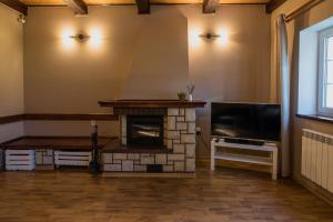 a living room with a fireplace and a flat screen tv at Letniskowa 30 - Całoroczny dom do wynajęcia in Ogonki