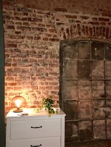 a brick wall with a white dresser with a candle on it at home2be apartments in Wuppertal