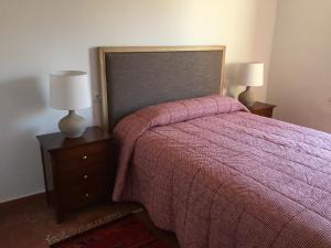 a bedroom with a bed with a pink blanket and two lamps at Casa Rural de Jaime in Medinaceli