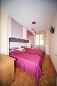ピエトラ・リーグレにあるMilanomareのピンクのシーツが備わる客室内のベッド2台