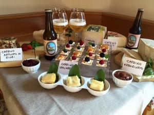 a table with appetizers and wine glasses and bottles of wine at Maso Toneto in Castello di Fiemme