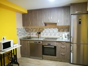 a kitchen with wooden cabinets and a stainless steel refrigerator at La Casina de Felix in Alles