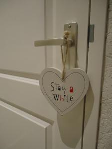a heart hanging on a door with the words stay a while at B&B Sloterpark in Amsterdam