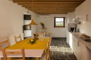 a kitchen and dining room with a yellow table and chairs at Quinta Nossa Senhora do Cabo in Lagoa