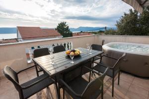 einen Tisch und Stühle auf einem Balkon mit einer Badewanne in der Unterkunft Apartments Ruzica in Pinezici