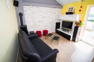 a living room with a black leather couch and a fireplace at Apartments Ruzica in Pinezici
