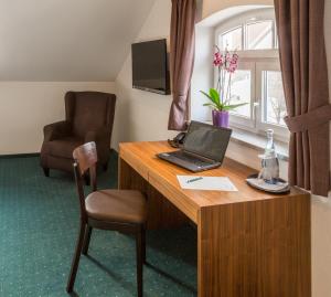 Pfaffing的住宿－法弗英霍夫酒店，客房配有带笔记本电脑和椅子的书桌