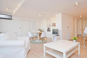 a white living room with a bed and a table at AticoColón21 in Alicante