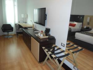 Habitación con escritorio, TV y cama. en Hotel San Silvestre, en Barrancabermeja